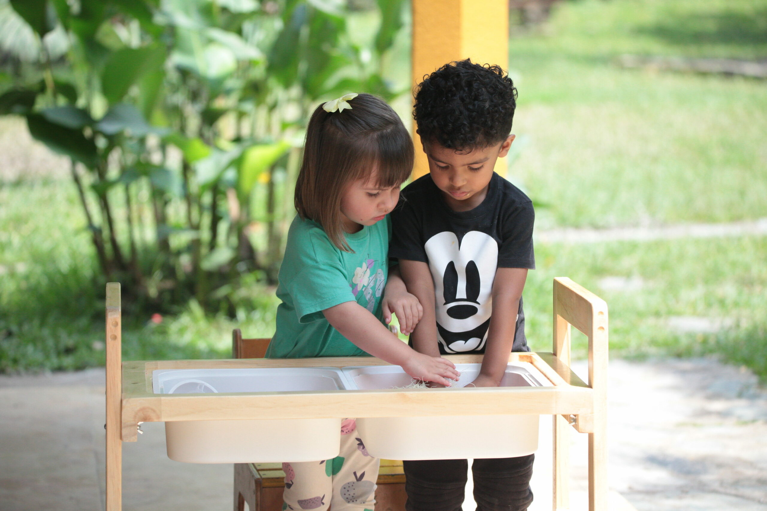 Dos estudiantes pequeños colaboran en una actividad práctica con agua.